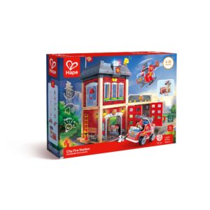 A boxed Hape ‘City Fire Station’ playset for ages 3–10, featuring a multi‑level fire station with a fire truck, helicopter, and small dog figure. The packaging highlights light and sound features, includes 13 pieces