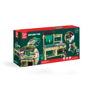 A boxed Hape ‘Nature Fun Outdoor Kitchen’ playset for ages 4–10, showing a wooden outdoor kitchen with a green sink, faucet, metal bowls, and storage shelves. The packaging features photos of children playing with the set, notes that it includes 15 pieces, and highlights its outdoor, eco‑friendly, imaginative‑play design.